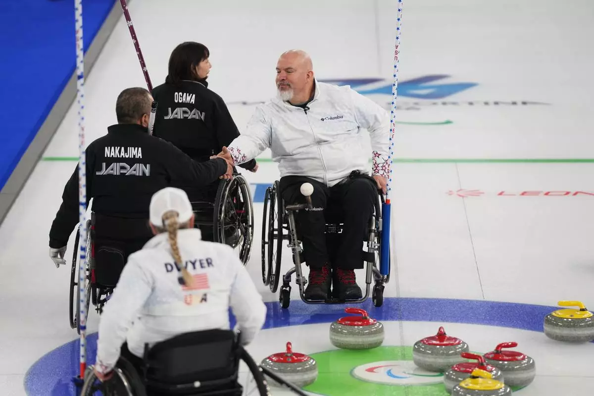 Steve Emt, right, and Laura Dwyer, of the United States, and Yoji Nakajima, left, and Aki Ogawa, of Japan, greet each other after their wheelchair curling mixed doubles round robin session at the 2026 Winter Paralympics, in Cortina d'Ampezzo, Italy, Thursday, March 5, 2026. (AP Photo/Evgeniy Maloletka)