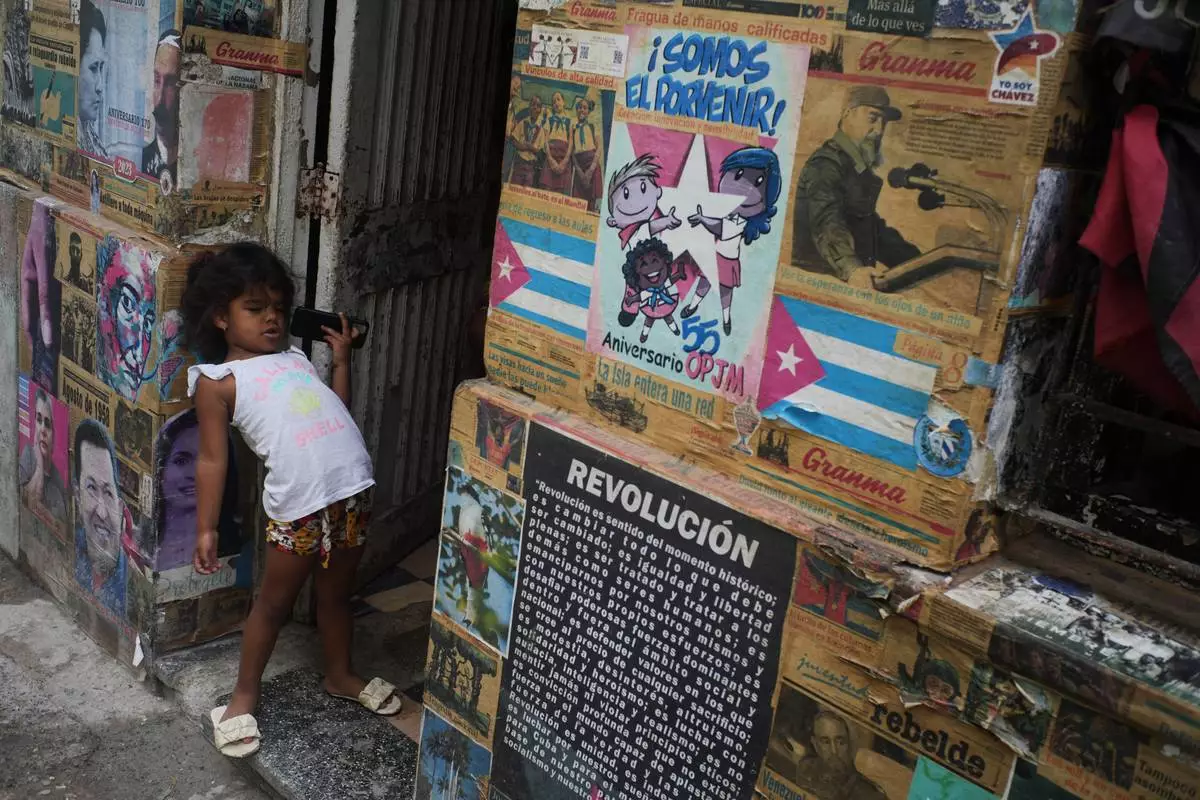 A girl plays in the doorway of the building where there is an art installation related to the Cuban Revolution, during a blackout in Havana, Tuesday, March 17, 2026. (AP Photo/Ramon Espinosa)
