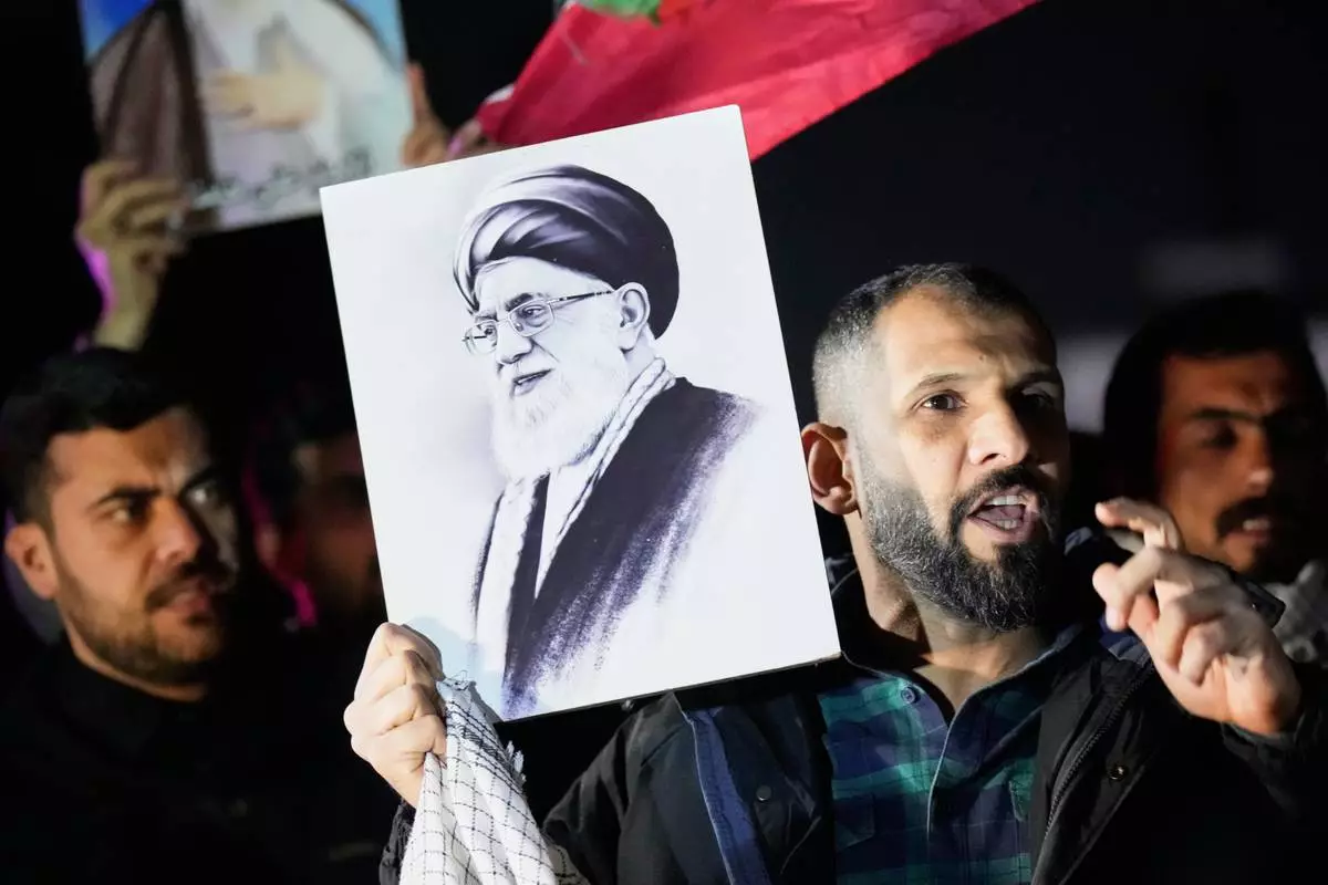 A protester holds a portrait of Iran's Supreme Leader Ayatollah Ali Khamenei during a protest against U.S. and Israeli attacks on multiple cities across Iran at a bridge leading to the fortified Green Zone where the U.S. Embassy is located in Baghdad, Iraq, Saturday, Feb. 28, 2026. (AP Photo/Hadi Mizban)