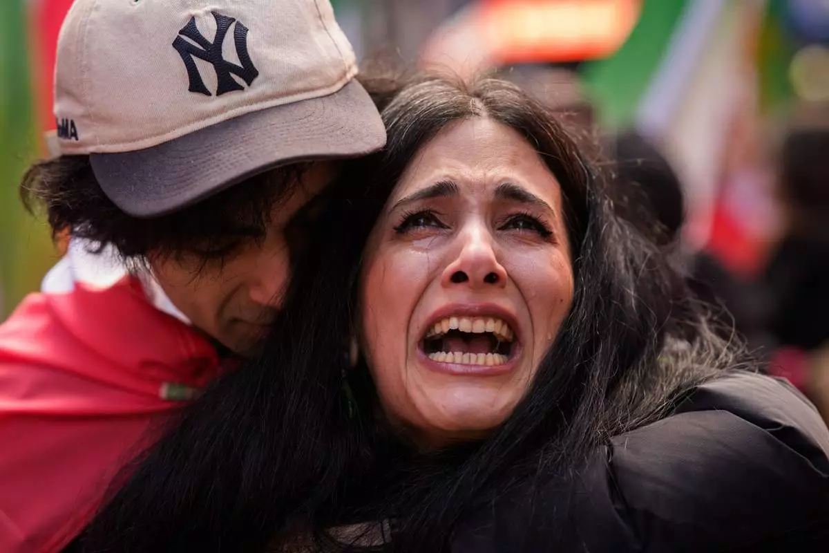 Noora cries as she is embraced by Pi, both Iranian, while singing a rendition of Iranian patriotic song Ey Iran, during a rally in reaction to U.S. and Israeli strikes on Iran, Sunday, March 1, 2026 in New York. (AP Photo/Adam Gray)