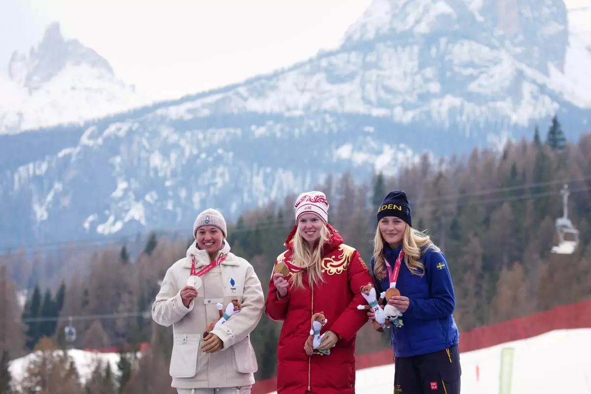 Silver medalist Aurelie Richard, of France, from left, gold medalist Varvara Voronchikhina, of Russia, and bronze medalist Ebba Aarsjoe, of Sweden, pose on the podium of the alpine skiing women's super-G standing at the 2026 Winter Paralympics, in Cortina d'Ampezzo, Italy, Monday, March 9, 2026. (AP Photo/Emilio Morenatti)