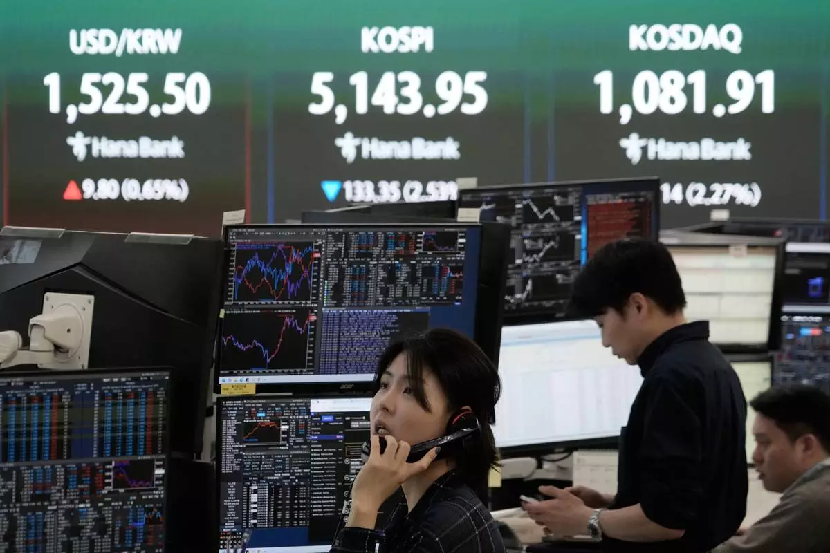 A currency trader talks on the phone near a screen showing the Korea Composite Stock Price Index (KOSPI), top center, and the foreign exchange rate between U.S. dollar and South Korean won, top center left, at the foreign exchange dealing room of the Hana Bank headquarters in Seoul, South Korea, Tuesday, March 31, 2026. (AP Photo/Ahn Young-joon)