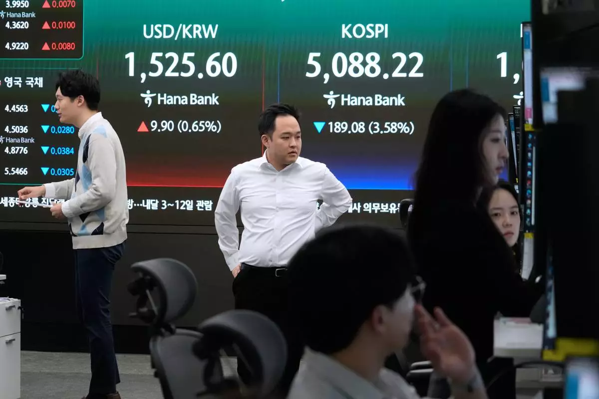 Currency traders work near a screen showing the Korea Composite Stock Price Index (KOSPI), top right, and the foreign exchange rate between U.S. dollar and South Korean won at the foreign exchange dealing room of the Hana Bank headquarters in Seoul, South Korea, Tuesday, March 31, 2026. (AP Photo/Ahn Young-joon)
