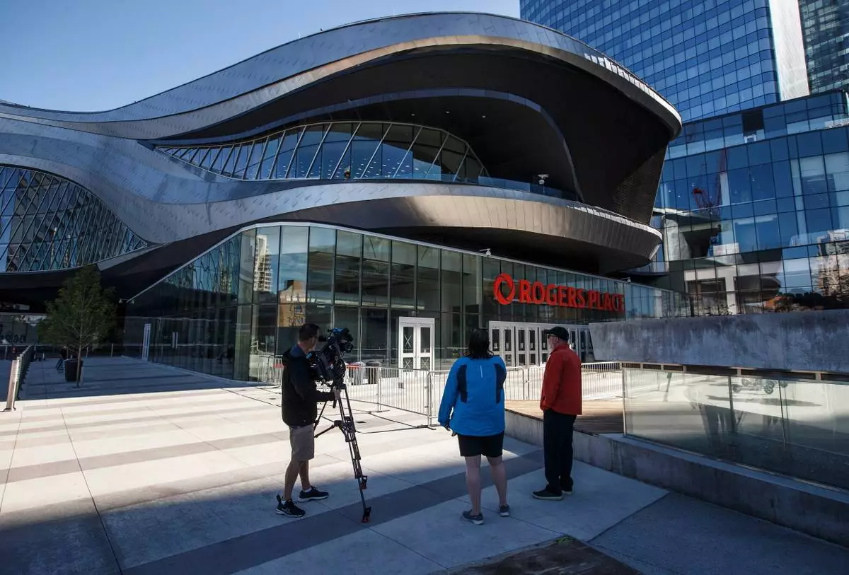 FILE - People stand outside Rogers Place, home of the Edmonton Oilers NHL hockey club, after it was damaged following flooding from a storm in Edmonton, Alberta, July 17, 2020. (Jason Franson/The Canadian Press via AP, file)