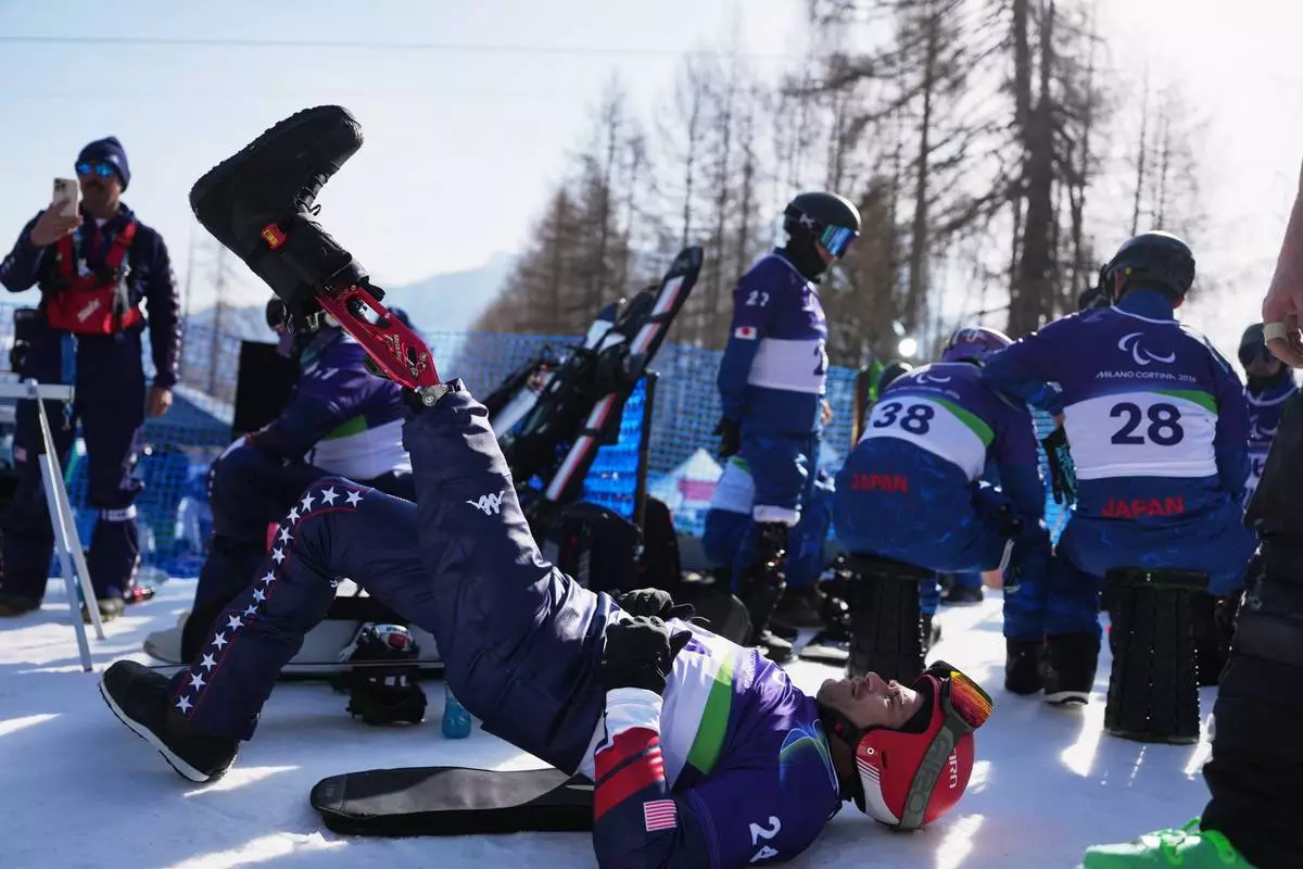 Mike Schultz, of the United States, stretches during warmup before the start of the snowboard cross competitions at the 2026 Winter Paralympics, in Cortina d'Ampezzo, Italy, Sunday, March 8, 2026. (AP Photo/Evgeniy Maloletka