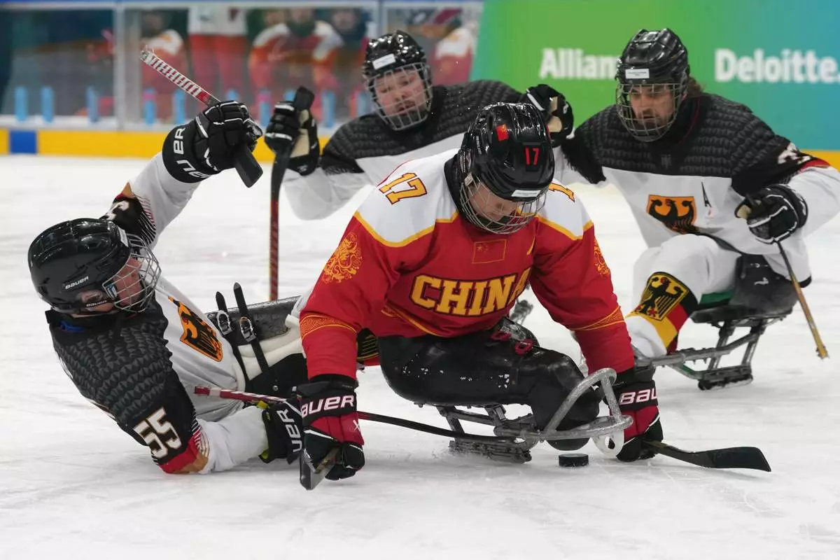Germany's Sven Stumpe, left, and China's Yifeng Shen challenge for the puck during the Group A hockey match between China and Germany at the 2026 Winter Paralympics, in Milan, Italy, Saturday, March 7, 2026. (AP Photo/Antonio Calanni)