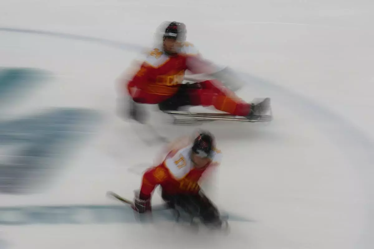 China's Zhanfu Zhu, top, and China's Yifeng Shen control the puck during the Group A hockey match between China and Germany at the 2026 Winter Paralympics, in Milan, Italy, Saturday, March 7, 2026. (AP Photo/Antonio Calanni)
