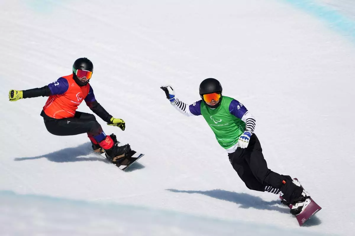 Lee Jehyuk, of South Korea, and Sun Qi, of China, left, compete in a men's snowboard cross SB-LL2 quarterfinal at the 2026 Winter Paralympics, in Cortina d'Ampezzo, Italy, Sunday, March 8, 2026. (AP Photo/Evgeniy Maloletka