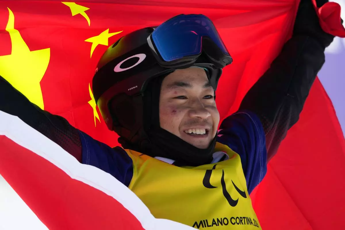 Wu Zhongwei, of China, celebrates after winning the gold medal in the men's snowboard cross SB-LL1 at the 2026 Winter Paralympics, in Cortina d'Ampezzo, Italy, Sunday, March 8, 2026. (AP Photo/Emilio Morenatti)