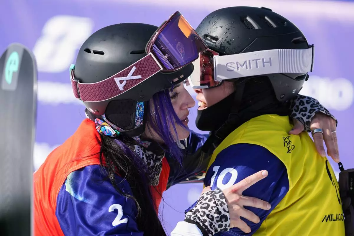 Brenna Huckaby, of the United States, left, embraces Eri Sakashita, of Japan, after finishing 6th in the women's snowboard cross SB-LL2 at the 2026 Winter Paralympics, in Cortina d'Ampezzo, Italy, Sunday, March 8, 2026. (AP Photo/Emilio Morenatti)