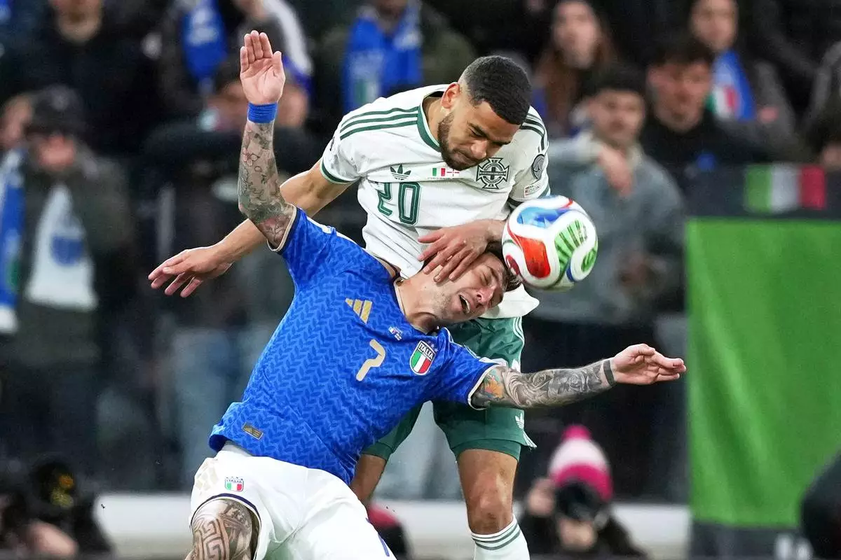 Italy's Matteo Politano, bottom, and Northern Ireland's Brodie Spencer vie for the ball during the World Cup qualifying play-off soccer match between Italy and Northern Ireland, in Bergamo, Italy, Thursday, March 26, 2026. (AP Photo/Antonio Calanni)
