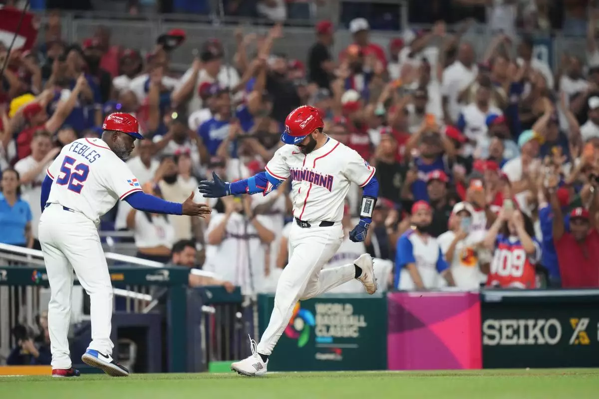 Dominican Republic's Austin Wells is congratulated by third base coach Carlos Febles as he heads for home after hitting a three-run home run to end the game early in the seventh inning of a World Baseball Classic quarterfinal game against South Korea, Friday, March 13, 2026, in Miami. (AP Photo/Lynne Sladky)
