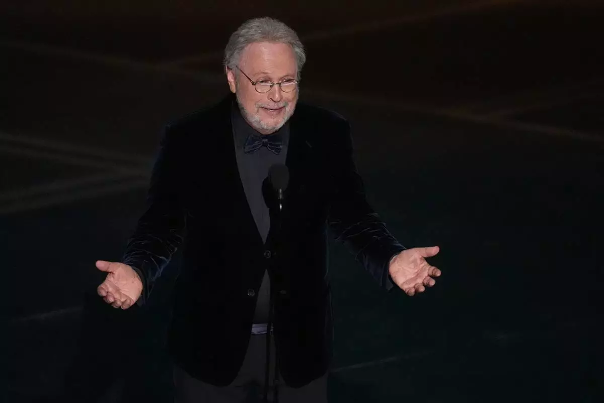 CORRECTS SPELLING OF MICHELE- Billy Crystal presents a tribute about Rob Reiner and Michele Singer Reiner during the Oscars on Sunday, March 15, 2026, at the Dolby Theatre in Los Angeles. (AP Photo/Chris Pizzello)