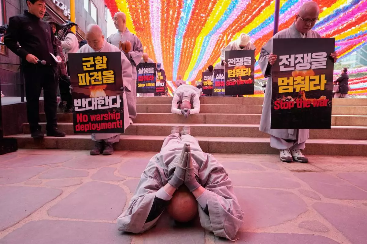 South Korean Buddhist monks and members of civic groups bow and prostrate themselves on the road as they march towards the U.S. Embassy in Seoul, South Korea, to protest against President Donald Trump asking multiple countries to send warships to reopen the Strait of Hormuz, Tuesday, March 17, 2026. (AP Photo/Ahn Young-joon)