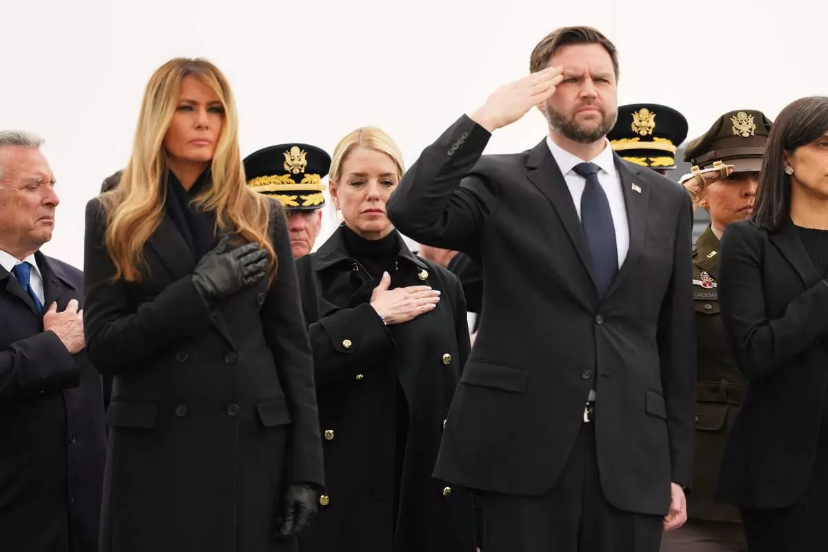 Attorney General Pam Bondi is seen standing between first lady Melania Trump and Vice President JD Vance during a casualty return for the soldiers who were killed in a drone strike at a command center in Kuwait after the U.S. and Israel launched its military campaign against Iran, Saturday, March 7, 2026, at Dover Air Force Base, Del. (AP Photo/Julia Demaree Nikhinson)