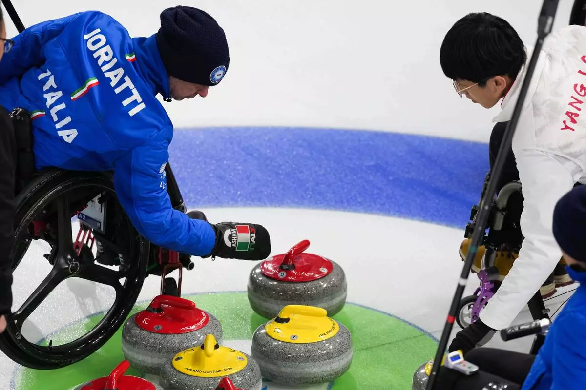 Paolo Ioriatti, left, of Italy, and Jinqiao Yang, right, of China, look at curling stones during a wheelchair curling mixed doubles at the 2026 Winter Paralympics, in Cortina d'Ampezzo, Italy, Thursday, March 5, 2026. (AP Photo/Evgeniy Maloletka)