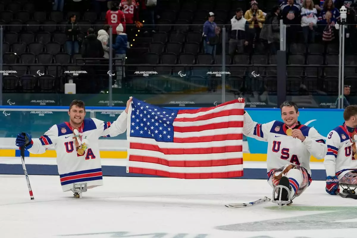 United States's Brody Roybal and his teammate Jack Wallace celebrate on the podium after winning the gold medal at the ice hockey of the 2026 Winter Paralympics, in Milan, Italy, Sunday, March 15, 2026. (AP Photo/Luca Bruno)