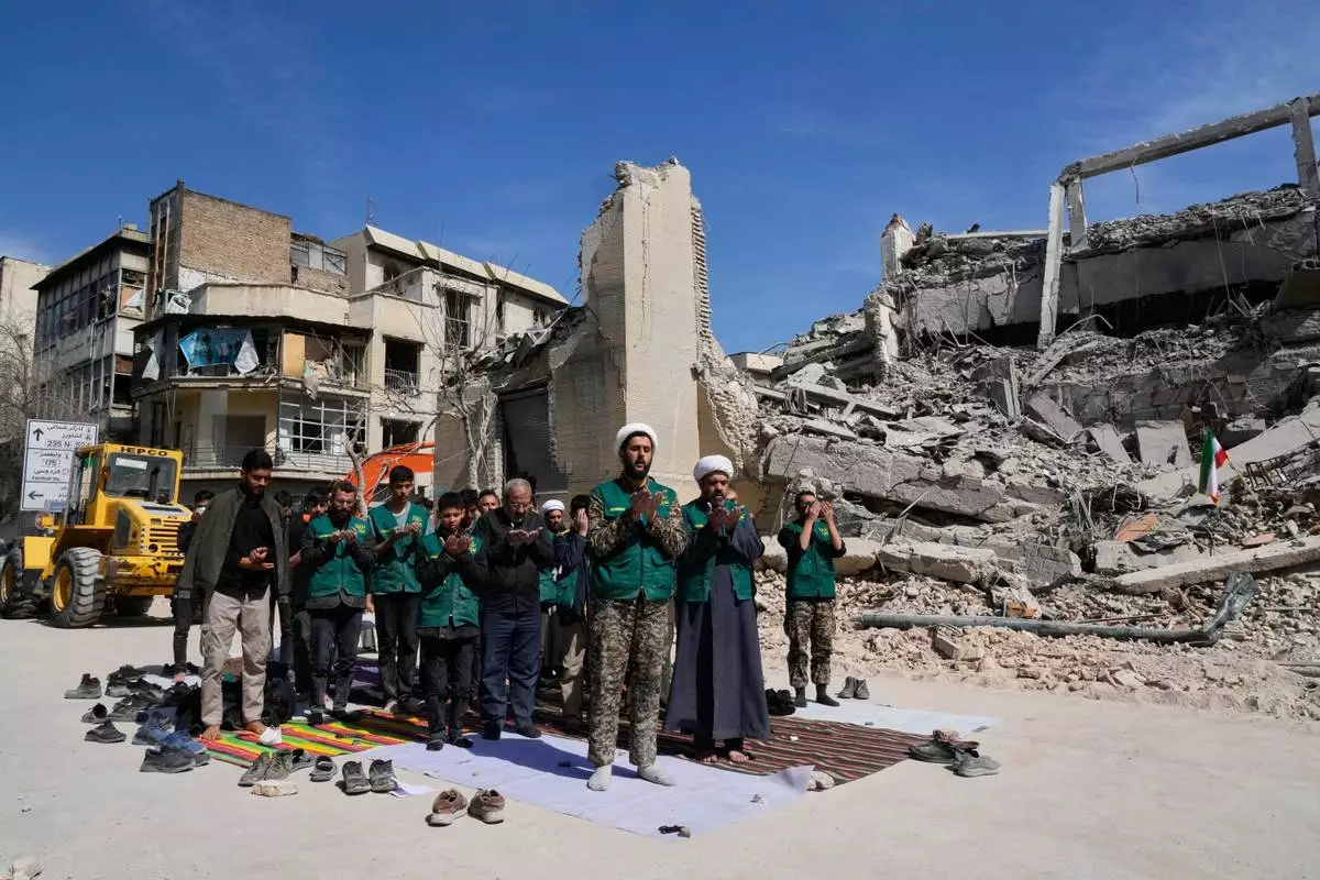 A cleric leads a group of volunteers in prayer next to a police facility struck during the U.S.–Israeli military campaign in Tehran, Iran, Wednesday, March 4, 2026. (AP Photo/Vahid Salemi)