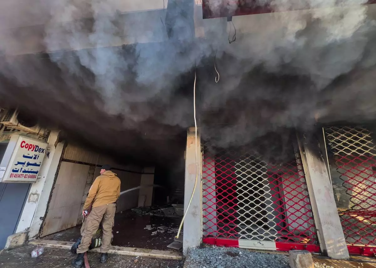A firefighter sprays water on a building that was hit by an Israeli airstrike in Dahiyeh, a southern suburb of Beirut, Lebanon, Tuesday, March 3, 2026. (AP Photo/Hussein Malla)