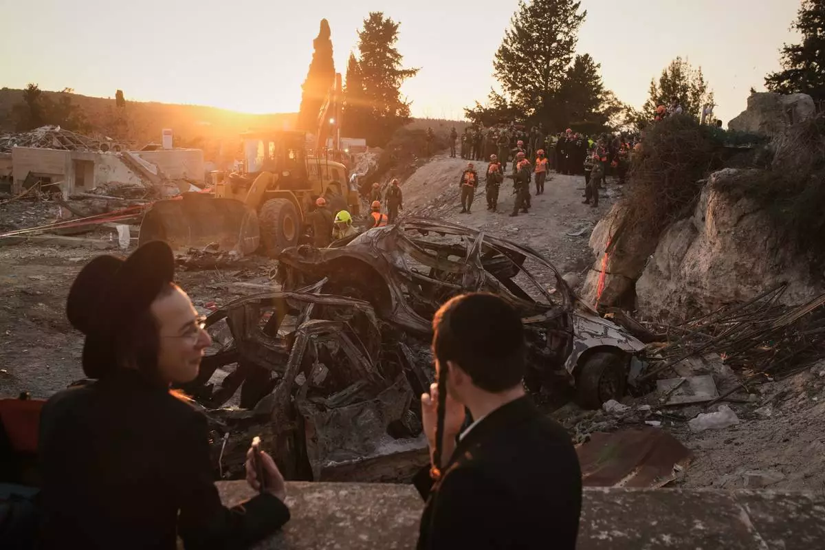 Ultra-Orthodox Jewish men watch as Israeli security forces operate at the site where several people were killed in an Iranian missile strike in Beit Shemesh, Israel, Sunday, March 1, 2026. (AP Photo/Leo Correa)