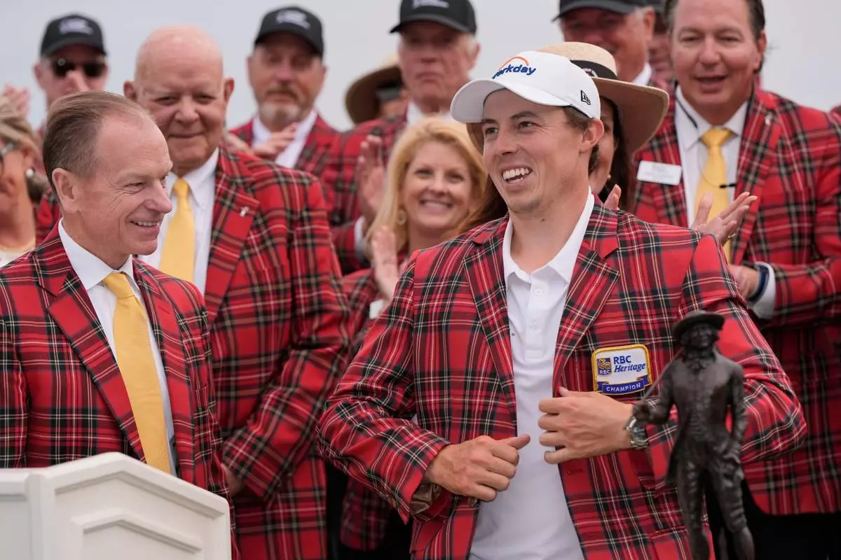Matt Fitzpatrick, of England, right, puts on the tartan plaid jacket after winning the RBC Heritage golf tournament Sunday, April 19, 2026, in Hilton Head, S.C. (AP Photo/Mike Stewart)