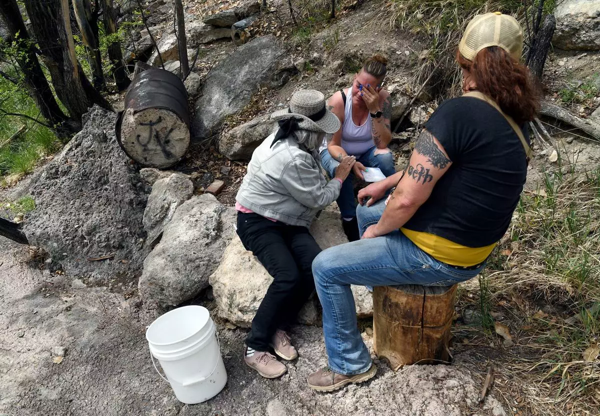 Crystina Page, whose son's body was among nearly 200 found decomposing in a southern Colorado funeral home in 2023, is comforted at a memorial site for the victims in Colorado Springs, Colo., on Wednesday, April 22, 2026. (AP Photo/Thomas Peipert)