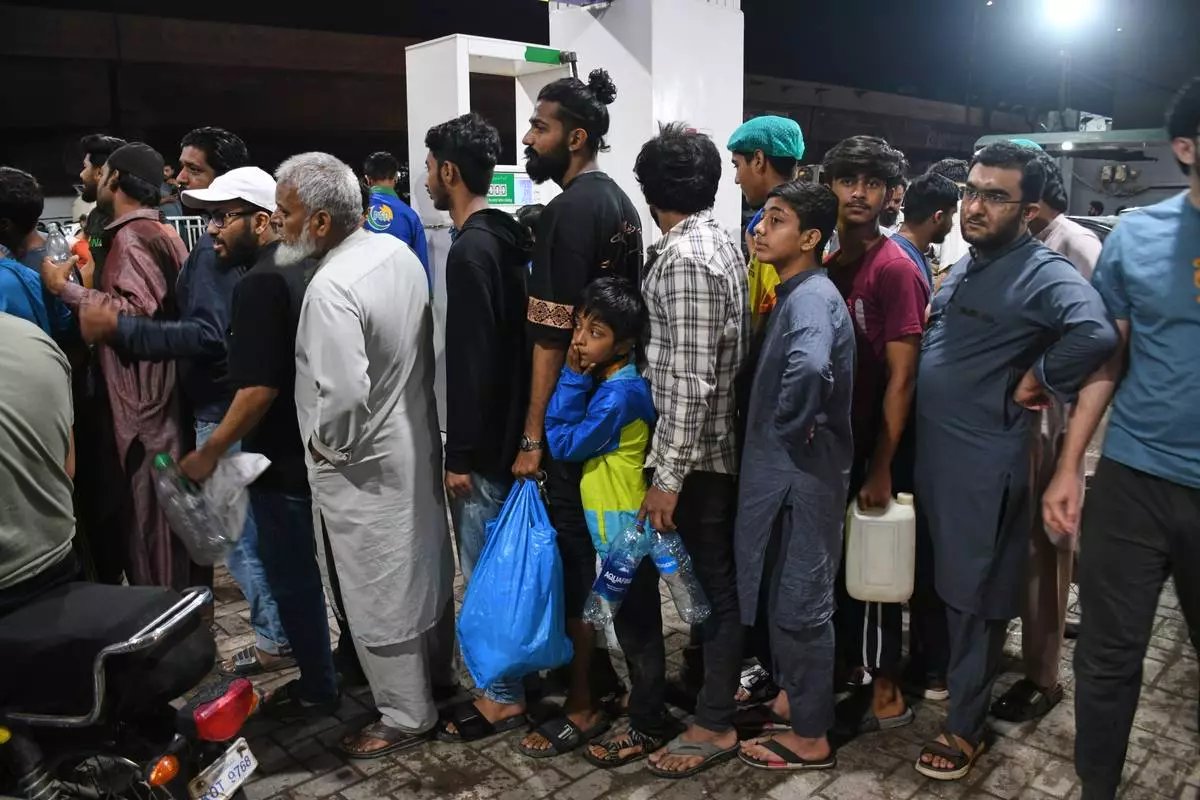 People stand in a queue at a filling station as they wait to fill their containers with gas in Karachi, Pakistan, Thursday, April 2, 2026. (AP Photo/Ali Raza)