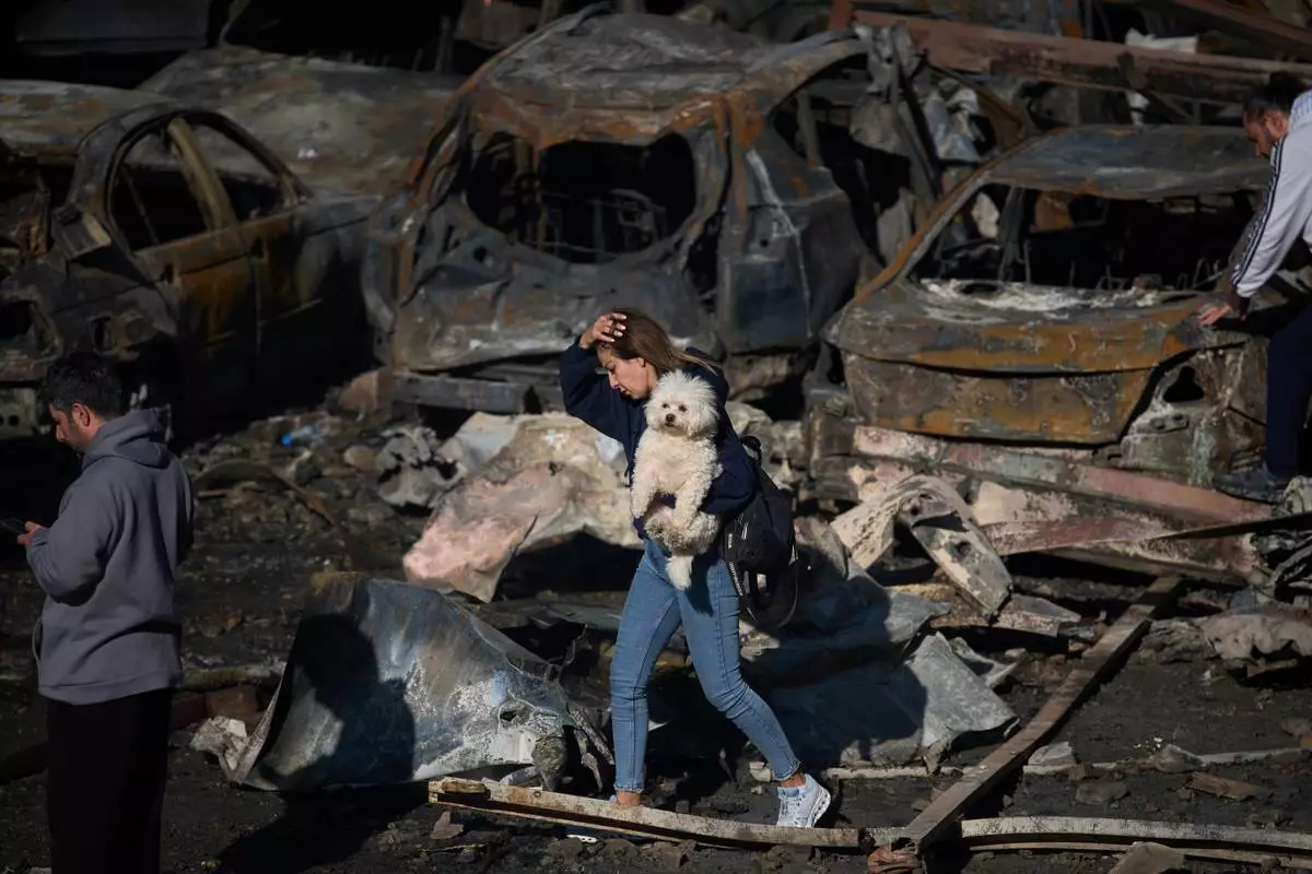FILE - A woman holds her dog as she walks past burned cars a day after an Israeli airstrike in Beirut, Lebanon, Thursday, April 9, 2026. (AP Photo/Emilio Morenatti, File)