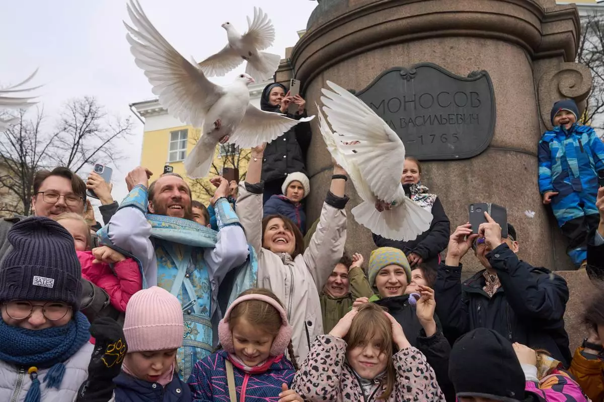 FILE - Orthodox priest Father Simeon, center left, with children and their parents, releases birds celebrating the Annunciation preceding the celebration of Orthodox Easter, in front of the Lomonosov Moscow State University and the St. Tatiana Church near the Kremlin, in Moscow, on Tuesday, April 7, 2026. (AP Photo/Alexander Zemlianichenko, File)
