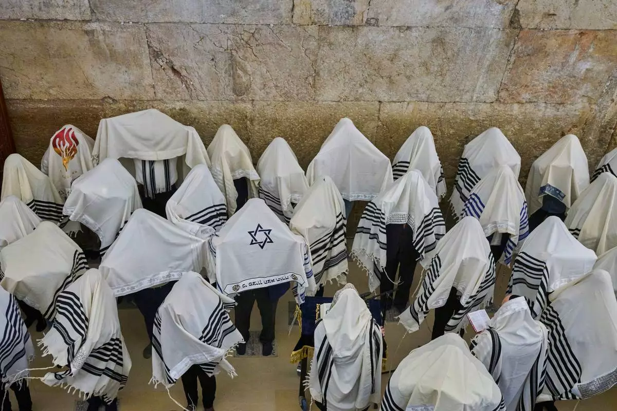 FILE - Ultra-Orthodox Jewish men pray during the priestly blessing on the Jewish holiday of Passover at the Western Wall, the holiest site where Jews can pray, in Jerusalem's Old City, largely empty due to restrictions linked to the Iran war, Sunday, April 5, 2026. (AP Photo/Ohad Zwigenberg, File)