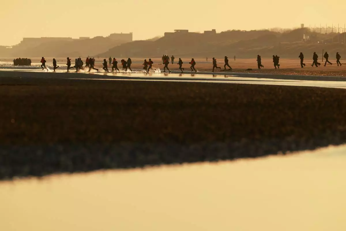 FILE - Migrants run to board a small boat in an attempt to reach Britain, Wednesday, April 8, 2026 in Malo-les-Bains, northern France. (AP Photo/Jean-Francois Badias, File)