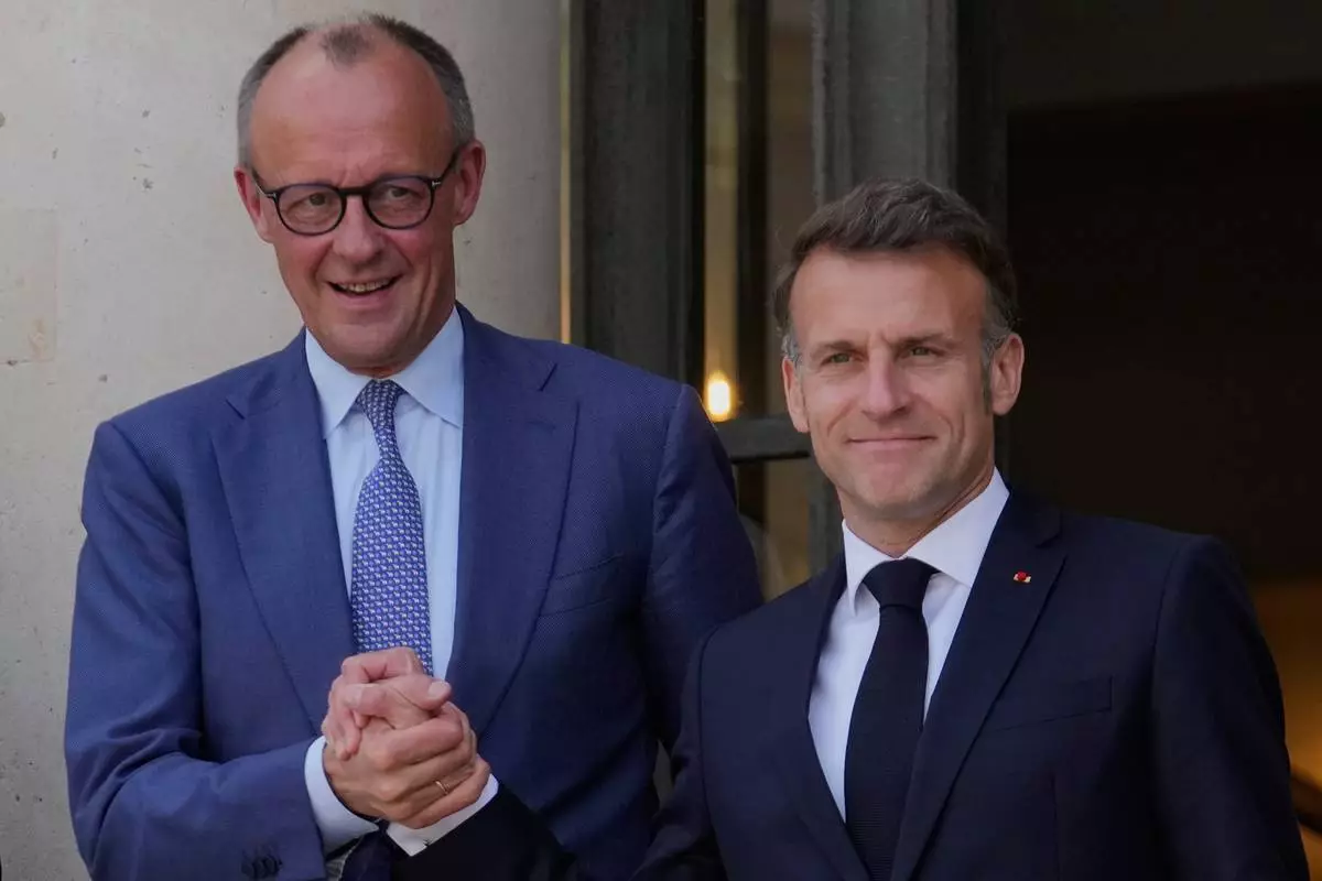 France's President Emmanuel Macron, right, welcomes German Chancellor Friedrich Merz prior to an international summit to push forward efforts to reopen the Strait of Hormuz, at the Elysee Palace, in Paris, France, Friday, April 17, 2026. (AP Photo/Michel Euler)