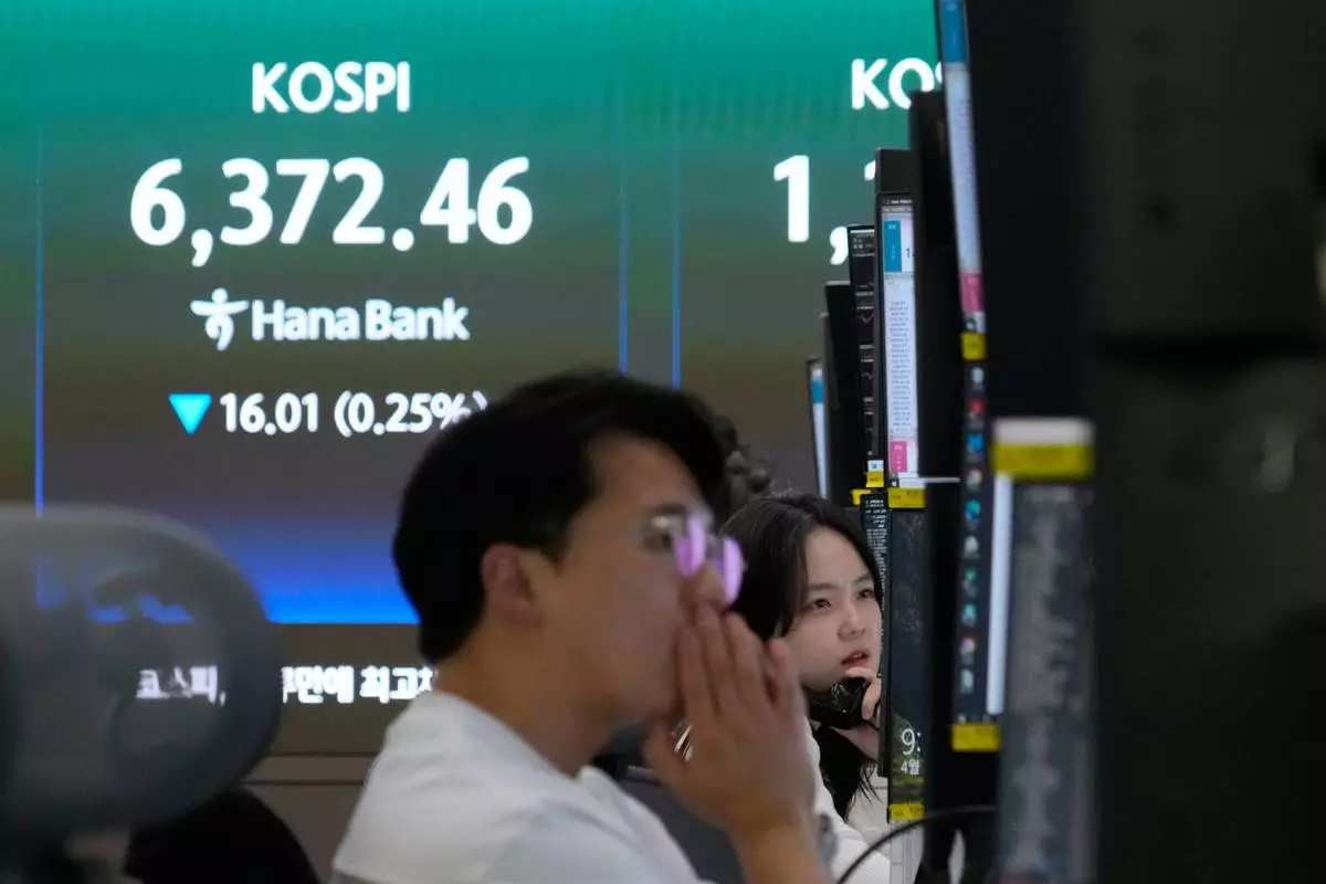 A currency trader talks on the phone near a screen showing the Korea Composite Stock Price Index (KOSPI) at the foreign exchange dealing room of the Hana Bank headquarters in Seoul, South Korea, Wednesday, April 22, 2026. (AP Photo/Ahn Young-joon)