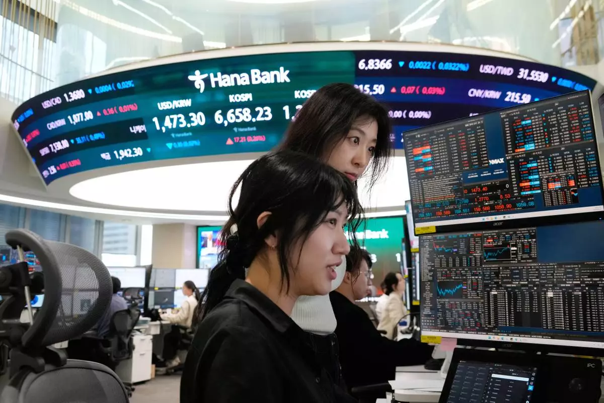 Currency traders watch monitors near a screen showing the Korea Composite Stock Price Index (KOSPI), top center, and the foreign exchange rate between U.S. dollar and South Korean won, top center left, at the foreign exchange dealing room of the Hana Bank headquarters in Seoul, South Korea, Wednesday, April 29, 2026. (AP Photo/Ahn Young-joon)