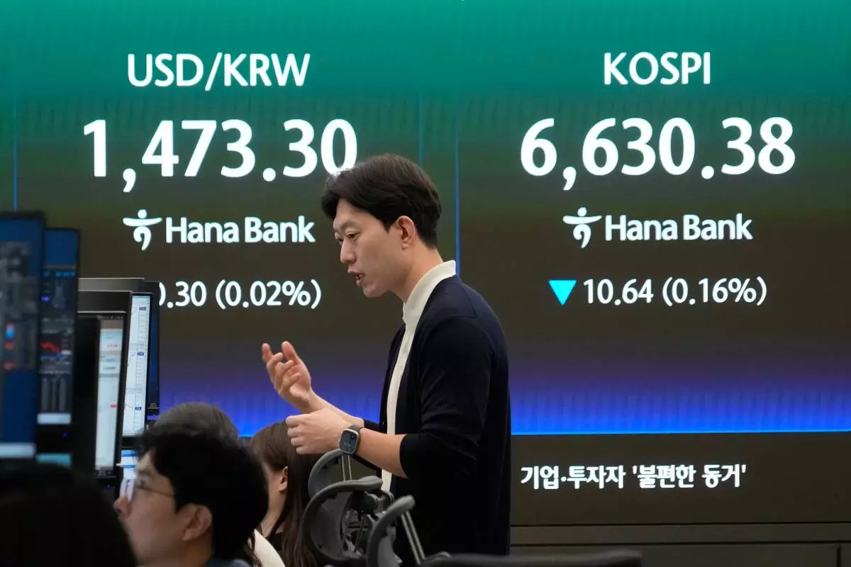 A currency trader reacts near a screen showing the Korea Composite Stock Price Index (KOSPI), right, and the foreign exchange rate between U.S. dollar and South Korean won at the foreign exchange dealing room of the Hana Bank headquarters in Seoul, South Korea, Wednesday, April 29, 2026. (AP Photo/Ahn Young-joon)