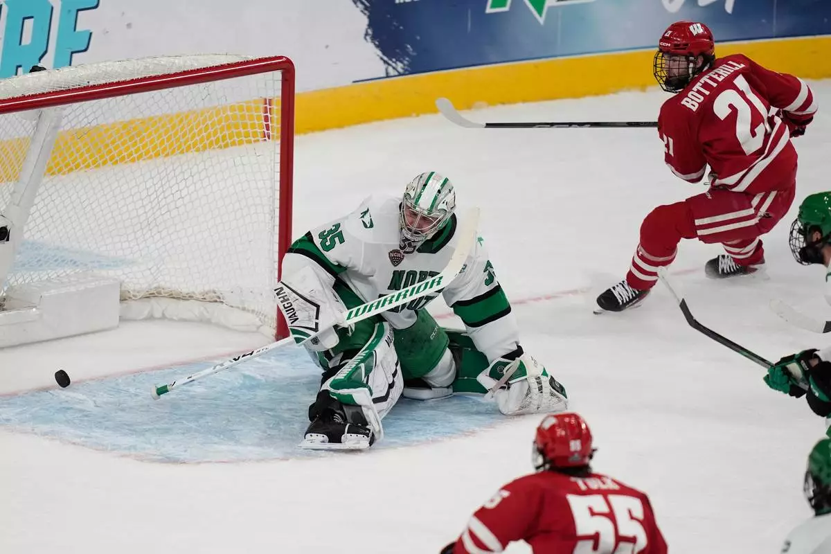 Wisconsin forward Ryan Botterill (21) scores against North Dakota goaltender Jan Spunar (35) in the first period of a semifinal game of the NCAA Frozen Four men's college hockey tournament Thursday, April 9, 2026, in Las Vegas. (AP Photo/John Locher)