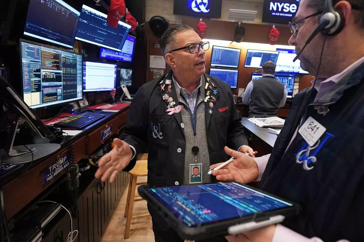 Traders Jonathan Mueller, left, and Michael Capolino confer on the floor of the New York Stock Exchange, Thursday, April 23, 2026. (AP Photo/Richard Drew)