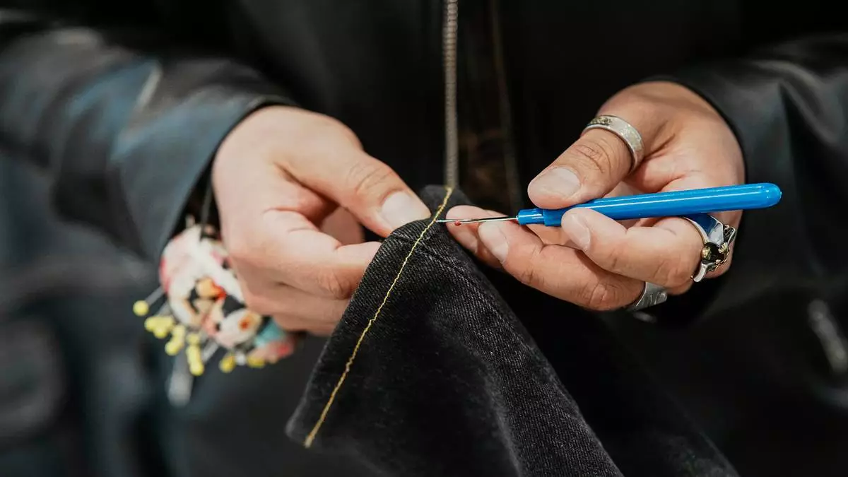 Tailor Marco Lema, 35, of Ecuador, works on a denim alteration at Nordstrom headquarters in New York, Monday, March 23, 2026. (AP Photo/Eduardo Munoz Alvarez)
