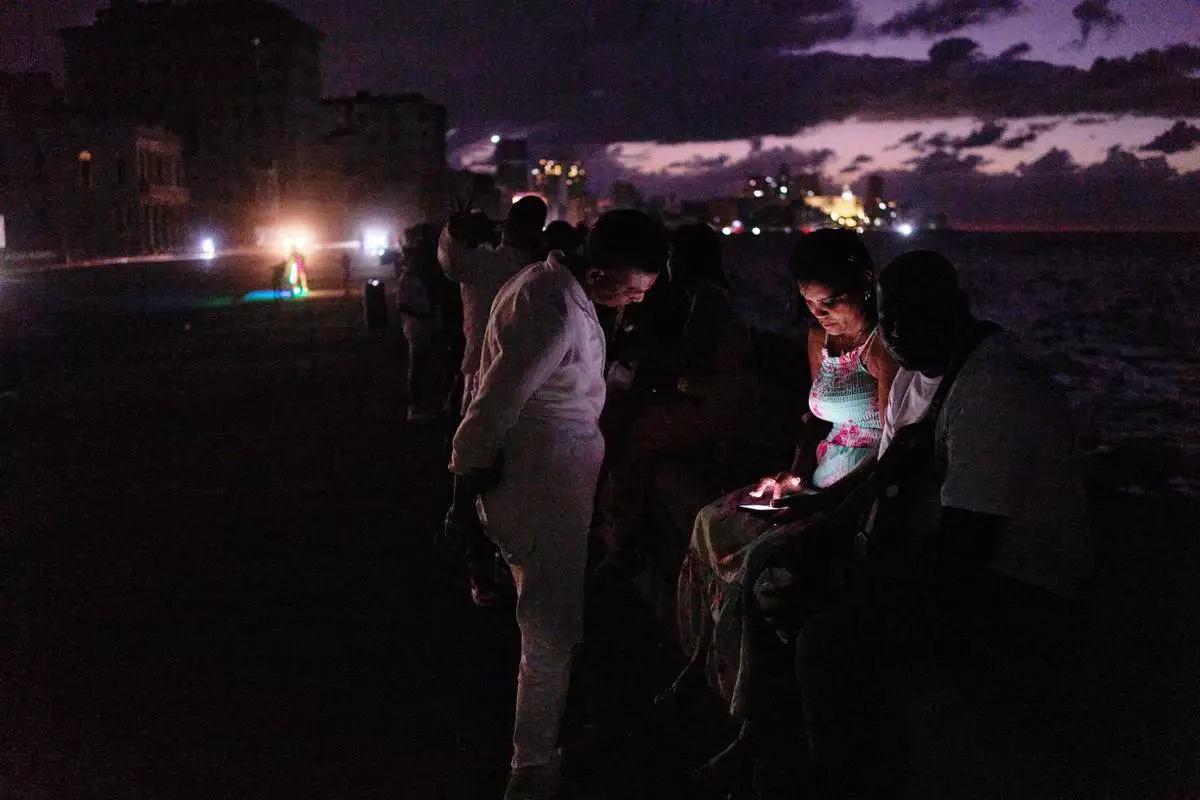 People spend the night in the dark on the Malecon during a blackout in Havana, Cuba, Saturday, March 21, 2026. (AP Photo/Ramon Espinosa)