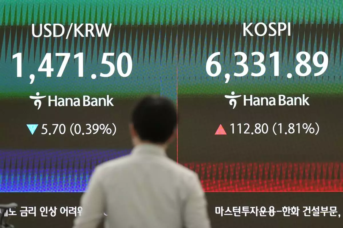 A dealer walks past the screens showing the Korea Composite Stock Price Index (KOSPI) and the foreign exchange rate between U.S. dollar and South Korean won at a dealing room of Hana Bank in Seoul, South Korea, Tuesday, April 21, 2026. (AP Photo/Lee Jin-man)