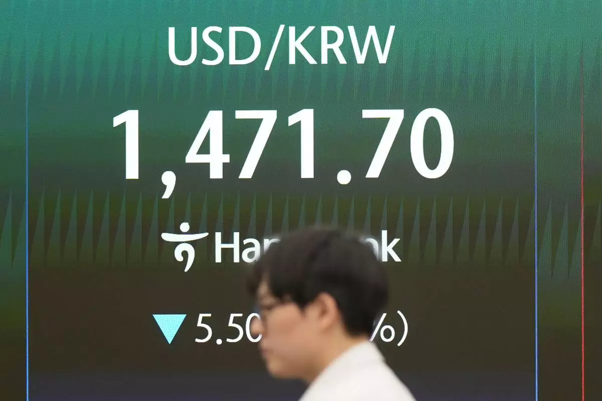 A dealer walks past the screen showing the foreign exchange rate between U.S. dollar and South Korean won at a dealing room of Hana Bank in Seoul, South Korea, Tuesday, April 21, 2026. (AP Photo/Lee Jin-man)