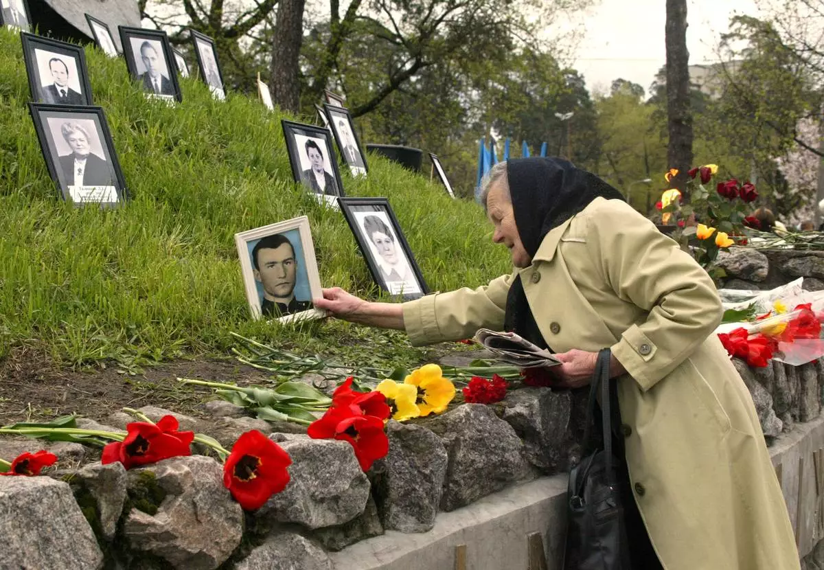 FILE - Praskoviya Nezhyvova places a photo of her son, Viktor, who died following cleanup operations from the 1986 Chernobyl nuclear plant accident, at a monument to the victims in Kyiv, April 26, 2004. (AP Photo/Efrem Lukatsky, File)