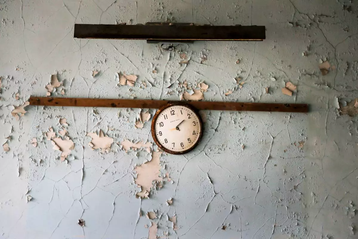 FILE - A broken clock hangs on a wall in a school in the deserted town of Pripyat, Ukraine, April 5, 2017, once home to people whose lives were connected to the Chernobyl nuclear power plant about 3 kilometers (nearly 2 miles) away. (AP Photo/Efrem Lukatsky, File)