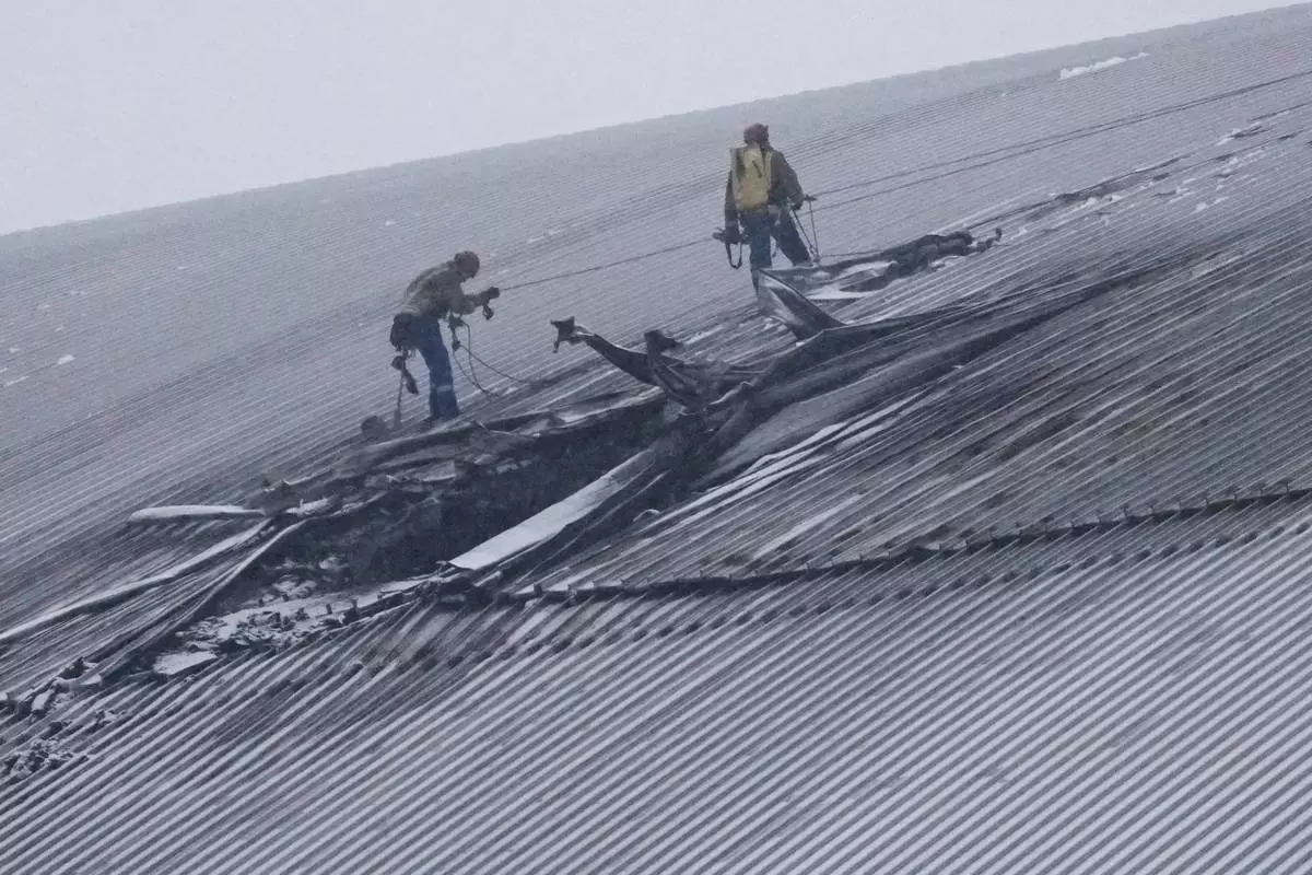 FILE - Workers examine the damage to the roof of the New Safe Confinement structure, which was built to contain the radioactive remains of Reactor No. 4 at the Chernobyl nuclear power plant, following what Ukrainian officials said was a Russian drone attack in Chernobyl, Ukraine, Feb. 14, 2025. (AP Photo/Efrem Lukatsky, File)