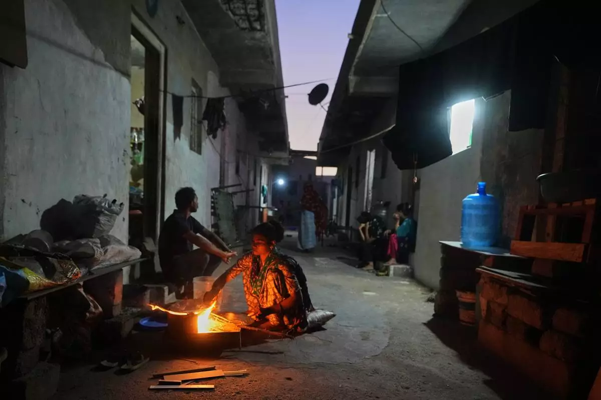 A migrant woman prepares a meal using firewood at a deserted ceramics workers' quarters in Morbi, in the Indian state of Gujarat, Wednesday, April 8, 2026. (AP Photo/Ajit Solanki)