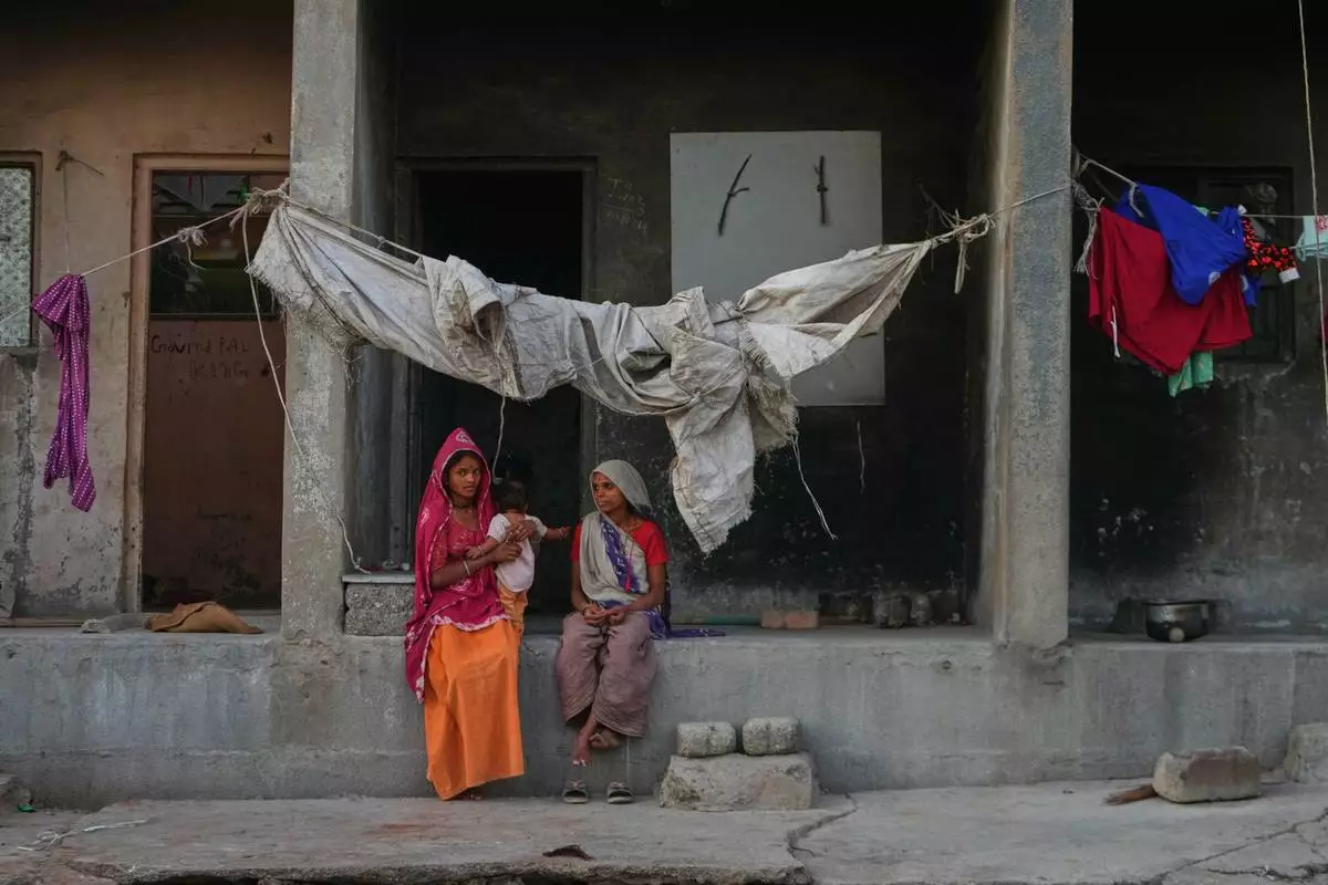 A migrant worker family sits in a deserted ceramics housing in Morbi, in the Indian state of Gujarat, Wednesday, April 8, 2026. (AP Photo/Ajit Solanki)