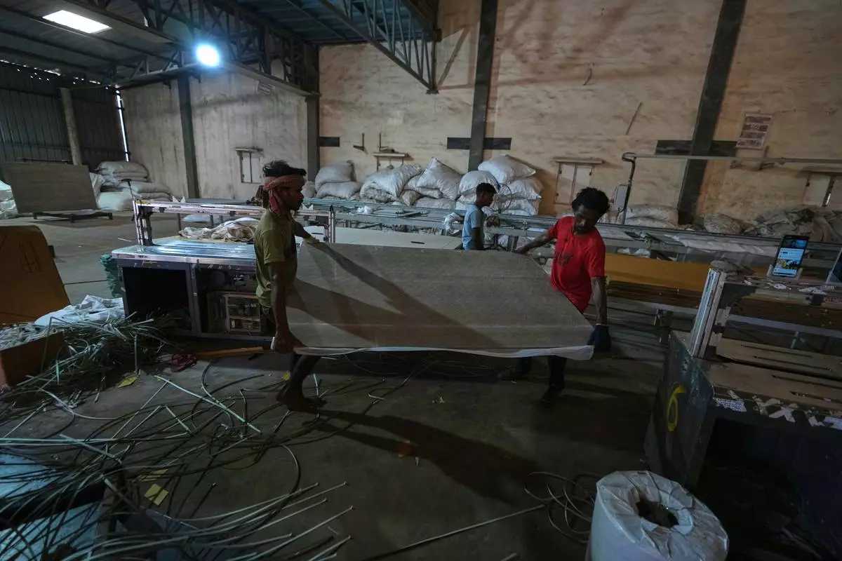Migrant workers carry ceramic tiles at a factory in Morbi, in the Indian state of Gujarat, Wednesday, April 8, 2026. (AP Photo/Ajit Solanki)