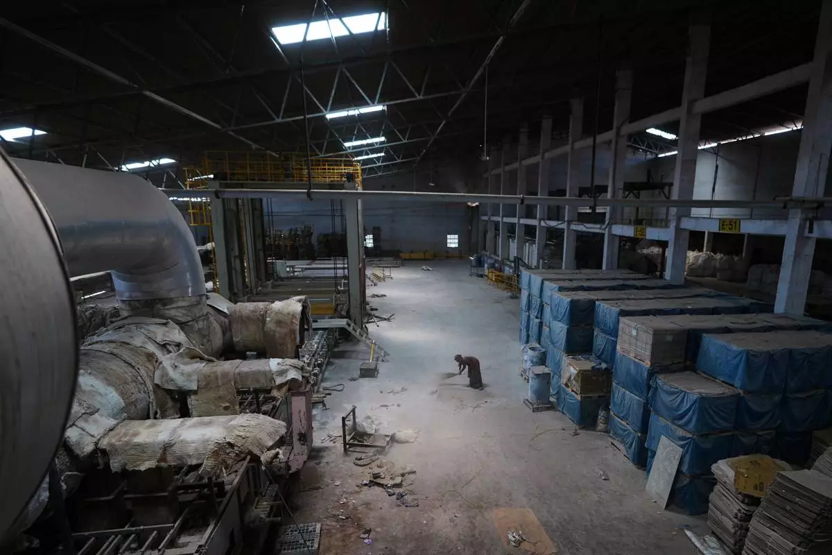 A worker sweeps the floor of a closed ceramics factory in Morbi,in the Indian state of Gujarat, Wednesday, April 8, 2026. (AP Photo/Ajit Solanki)