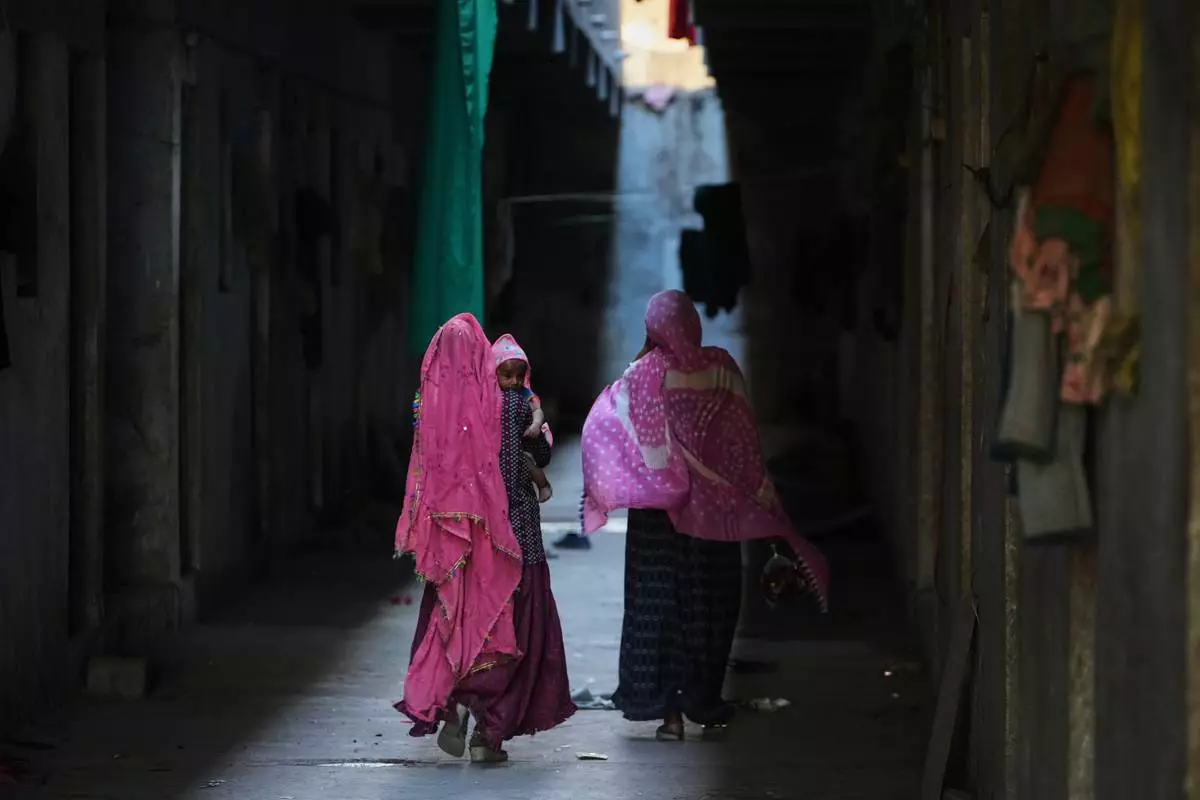 A family of migrant workers returns to their quarters in Morbi, in the Indian state of Gujarat, Wednesday, April 8, 2026. (AP Photo/Ajit Solanki)