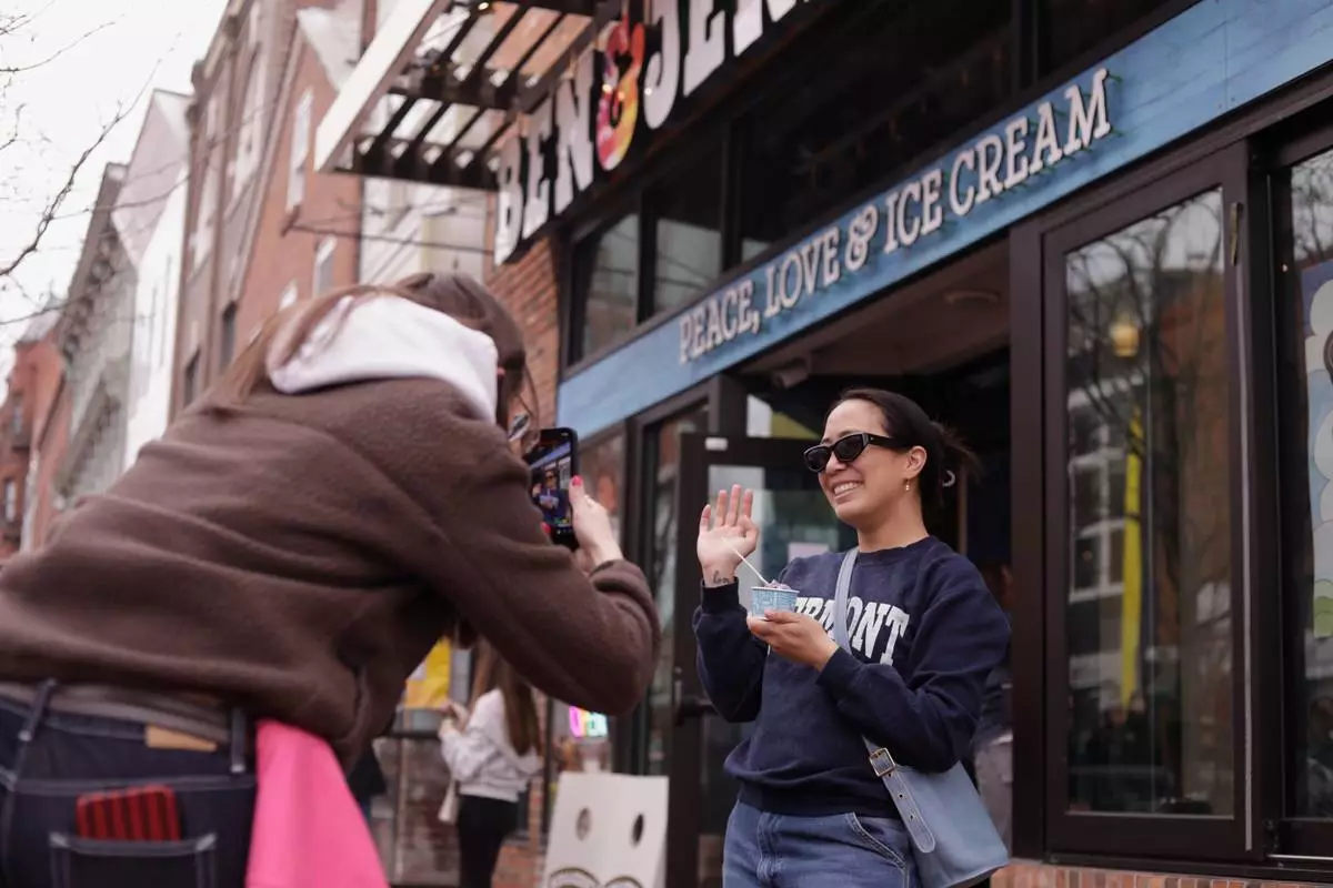 Bettina Guevara poses for a photo with her free serving of ice cream outside the Ben and Jerry's scoop shop on Free Cone Day in Burlington, Vt., Tuesday, April 14, 2026. (AP Photo/Amanda Swinhart)